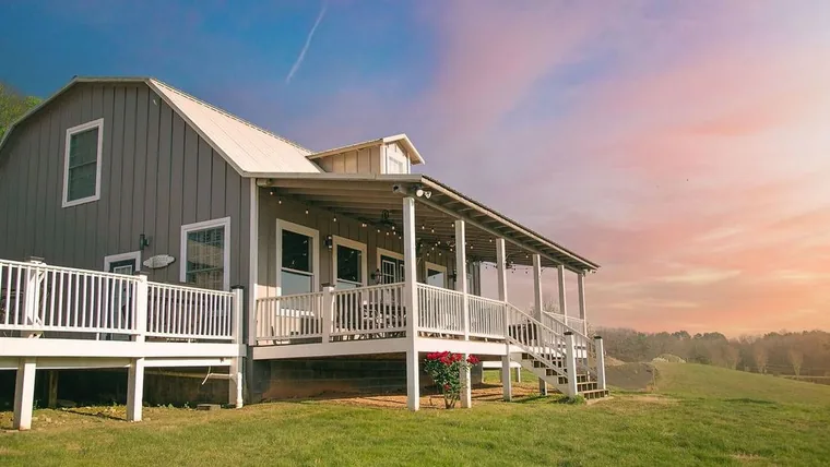 The Milkbarn farm stay at Cedar Pond Farms with its long porch, sleeping sixteen guests near Douglas Lake